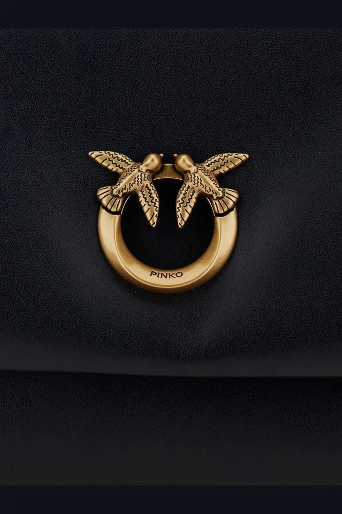 Gold-tone metal clasp with two detailed birds on a circular ring engraved pinko on black soft leather crossbody bag