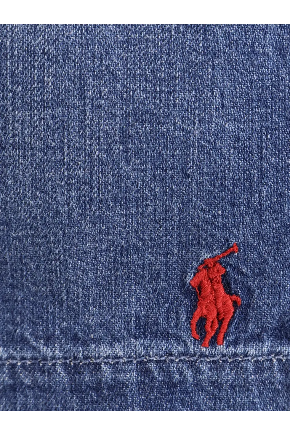 Red embroidered polo player logo on blue denim fabric of polo ralph lauren men’s denim bermuda shorts blane
