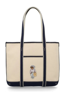 Cream-colored canvas tote bag with navy blue trim and bear character embroidery by Polo Ralph Lauren