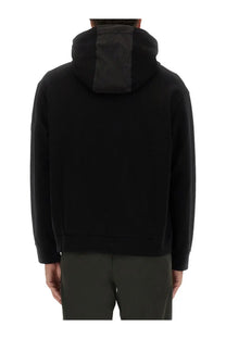 Back side of premiata men’s black hooded zip sweatshirt with contrasting dark gray panel on the center back