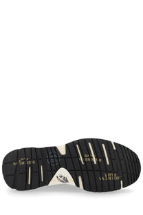 Black rubber sole with white accents and gold lettering featuring a triangular logo on the back of premiata women’s sneaker mased beige