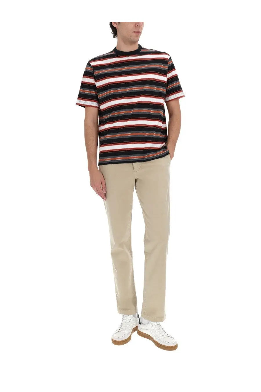 A man wearing a short-sleeved striped t-shirt with black white red bands paired with ps by paul smith brown chino pants