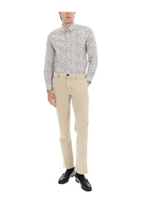 A man wearing a Ps By Paul Smith men’s white long-sleeved printed shirt with black abstract patterns and beige chinos