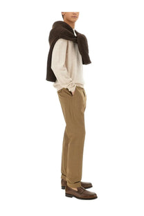 A man wearing pt torino men’s straight leg beige cotton pants paired with a beige shirt and brown leather loafers