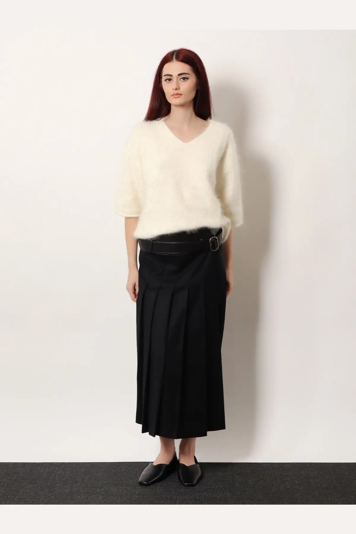 Cream-colored fluffy v-neck short sleeve wool sweater paired with R2W women’s nayla pleated black wool trousers skirt