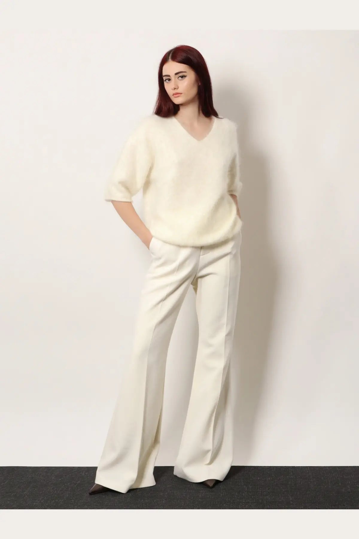 Cream-colored soft-knit v-neck sweater with short sleeves paired with r2w women’s vonnie wool white trousers