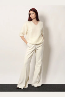 Cream-colored soft-knit v-neck sweater with short sleeves paired with r2w women’s vonnie wool white trousers