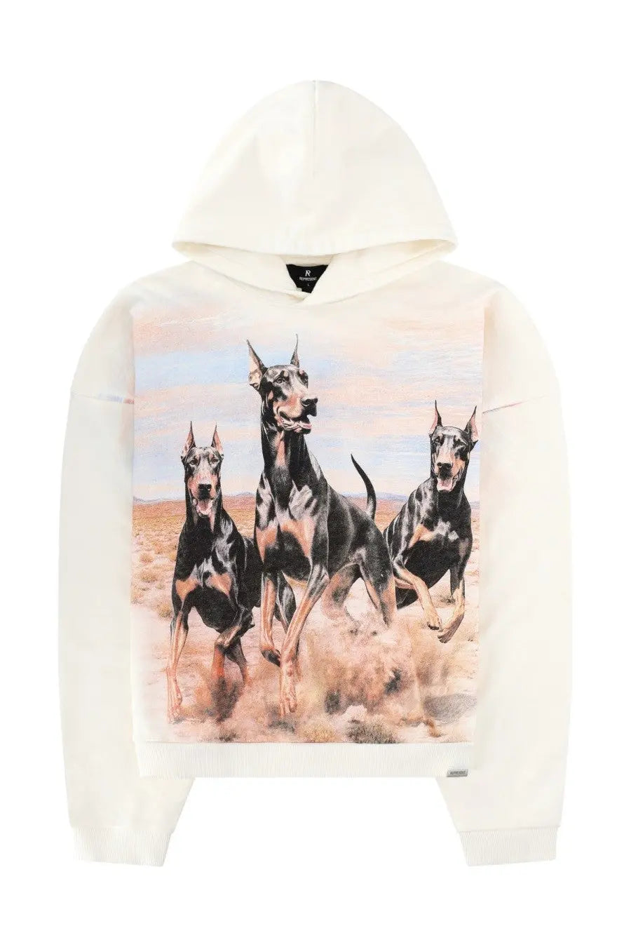 Cream-colored Represent men’s hoodie with detailed graphic of three running black and tan doberman pinschers in desert