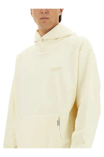 Cream-colored represent men’s hoodie beige with hood, subtle embroidered logo on chest, and small tag near pocket