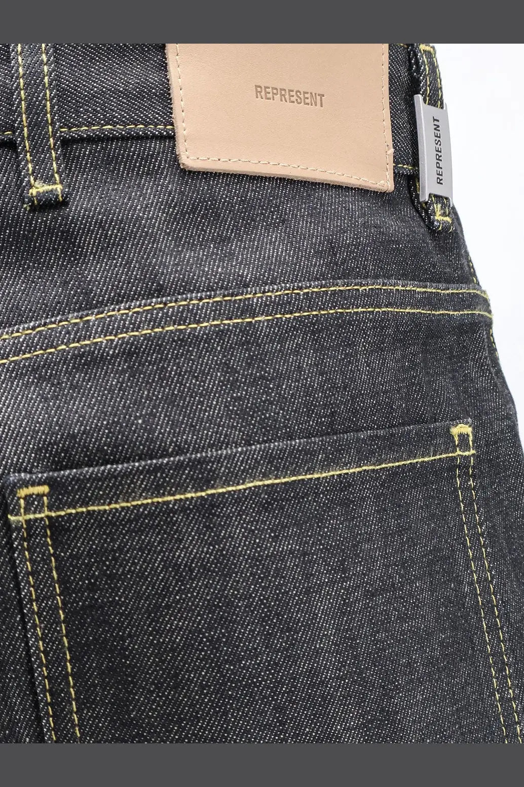 Represent men’s selvedge denim shirt black styled with dark-wash denim jeans featuring yellow stitching and beige leather patch