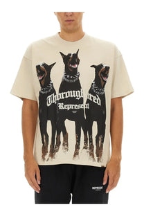 Cream-colored oversized men’s t-shirt featuring bold graphic of three black doberman pinschers with studded collars and thoroughbred represent text