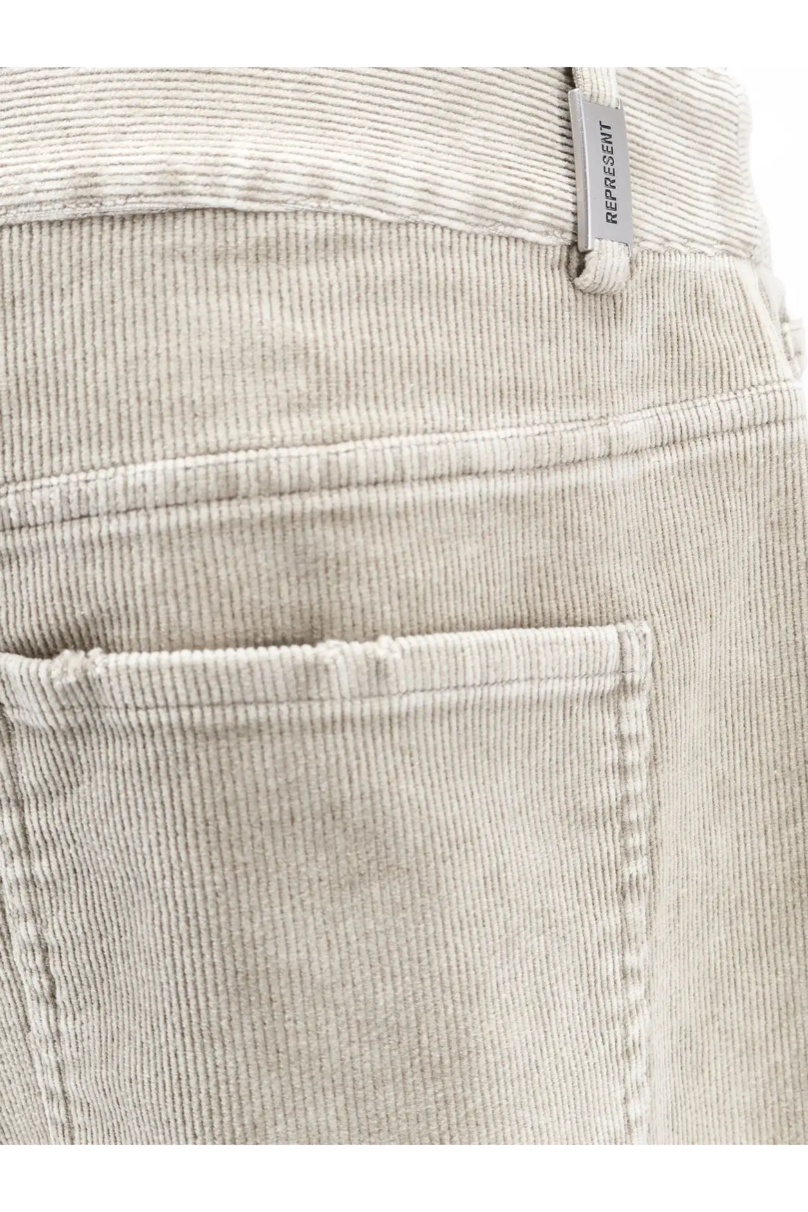Beige corduroy men’s trousers with subtle ribbed texture and represent branded tag at waistband