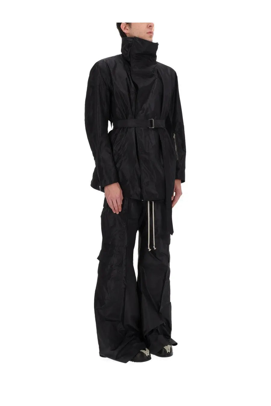 Rick Owens men’s black cargo belas pants paired with a black high-necked trench coat with belted waist and long sleeves