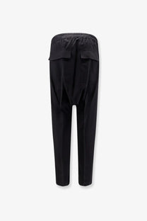 Back view of black rick owens men’s tapered virgin wool trousers with elastic waistband and two flap pockets