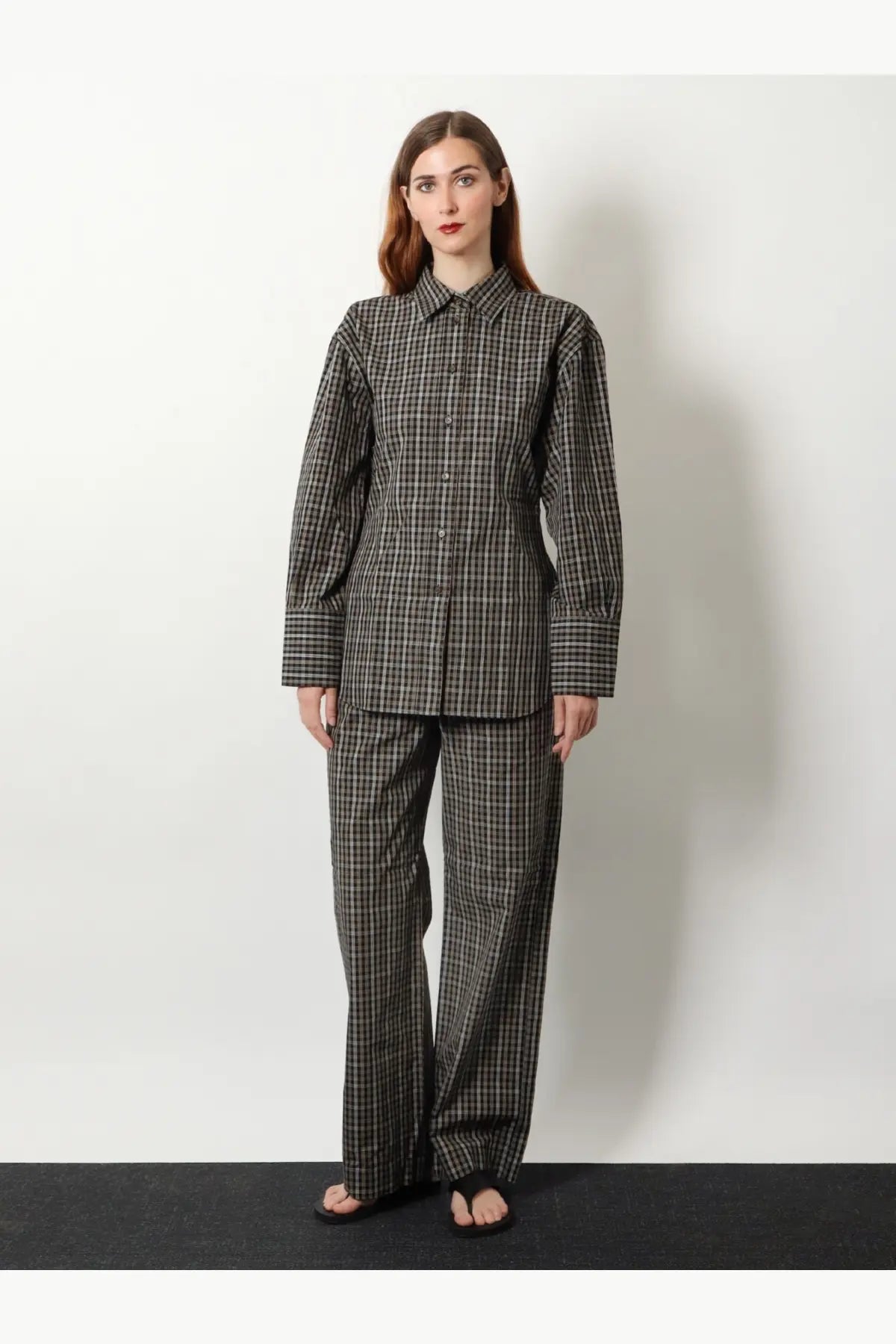 A woman wears rohe women’s black cotton shirt with tailored long sleeves and matching wide-leg checkered trousers