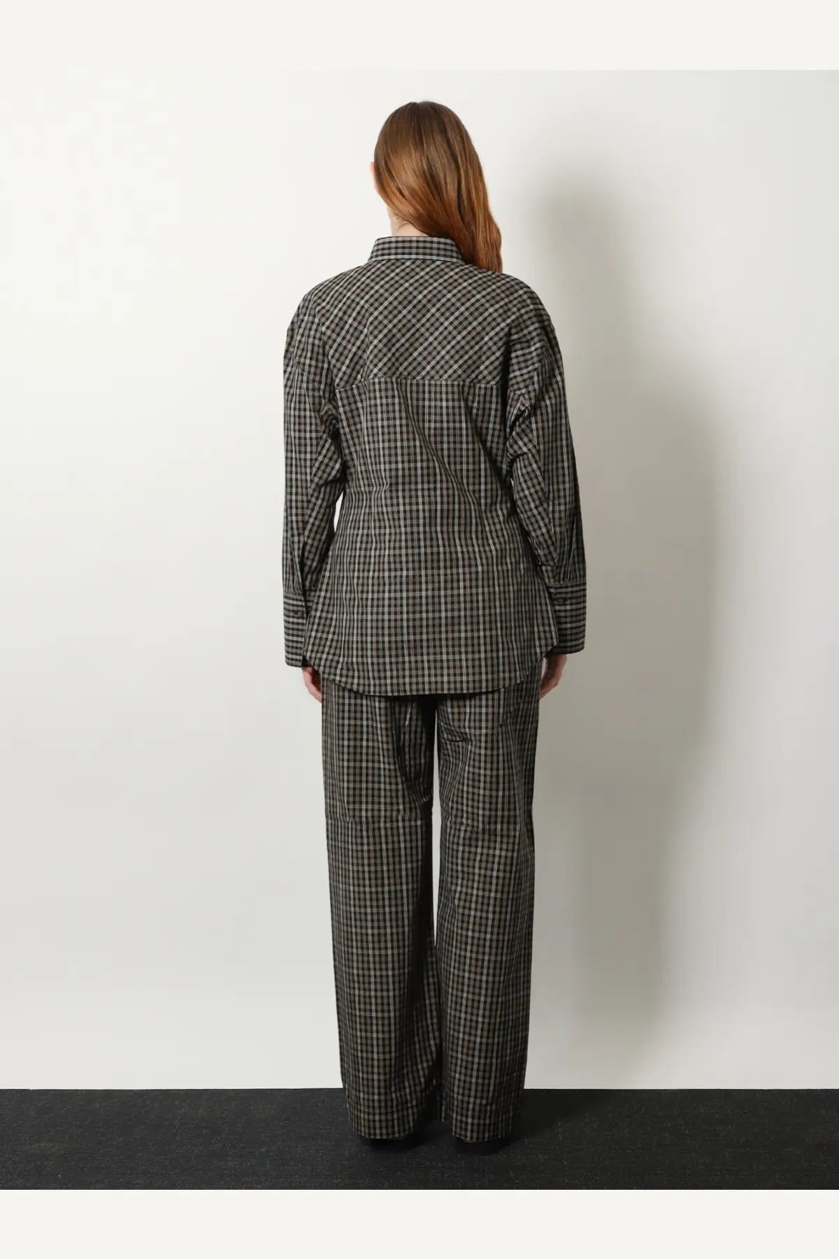 A woman wears rohe women’s black cotton shirt in black and white plaid matching oversized button-up and wide-leg trousers