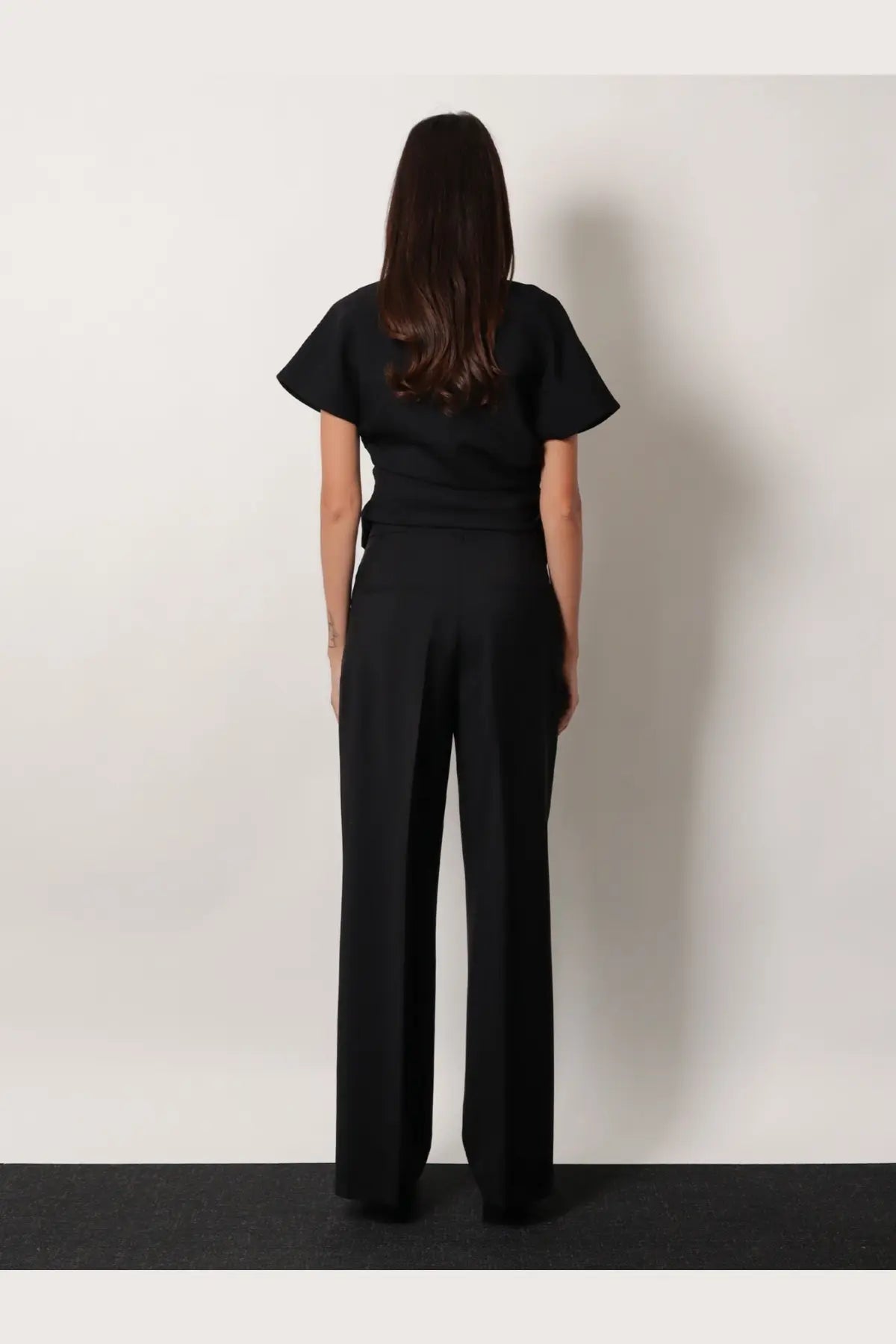 Rohe women’s midwaist wool blend trousers black paired with a black short-sleeved top with ruffled sleeves