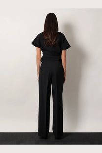 Rohe women’s midwaist wool blend trousers black paired with a black short-sleeved top with ruffled sleeves