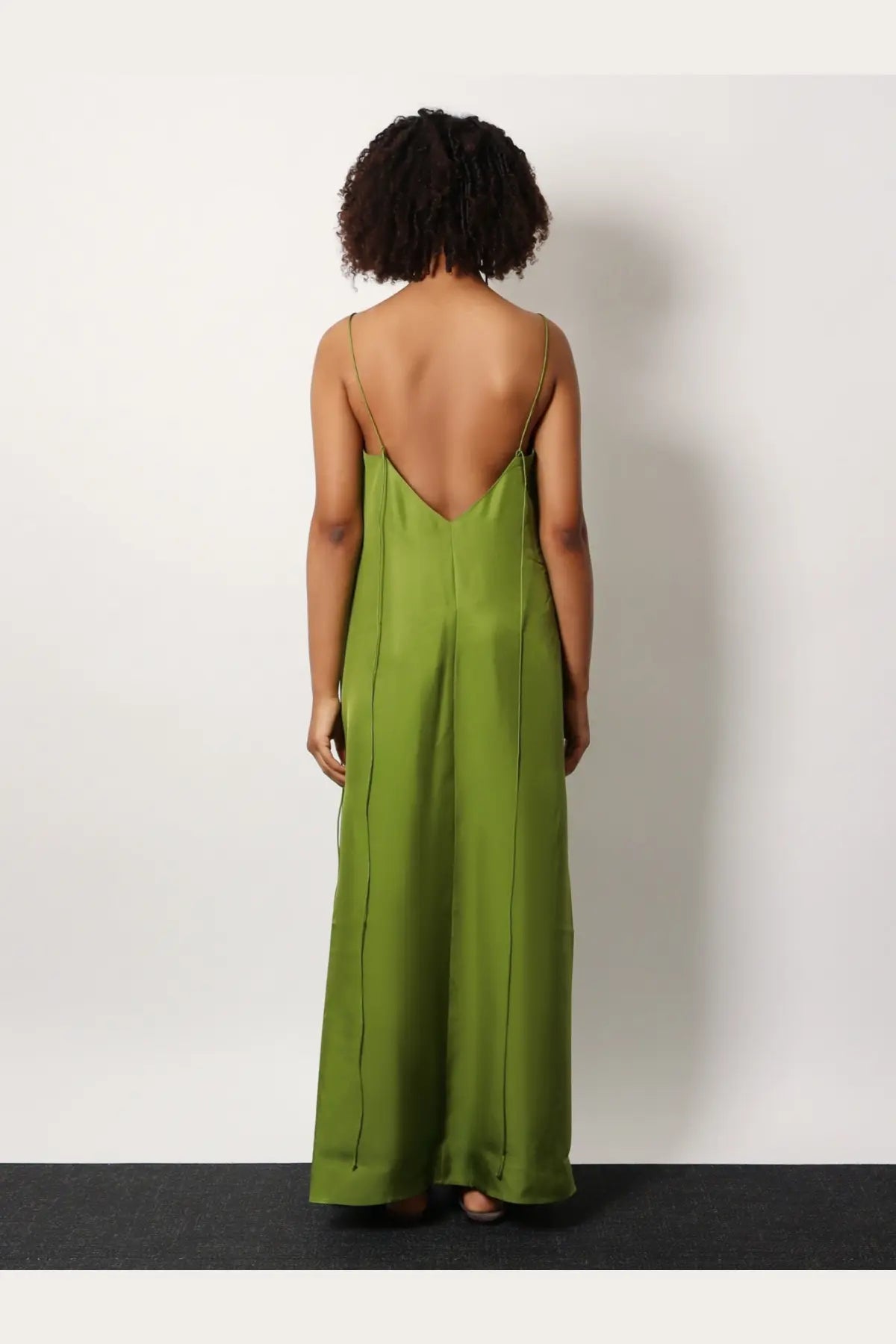 Rohe women’s silk dress green showing back side featuring a flowing olive green satin maxi with thin straps and deep cutout