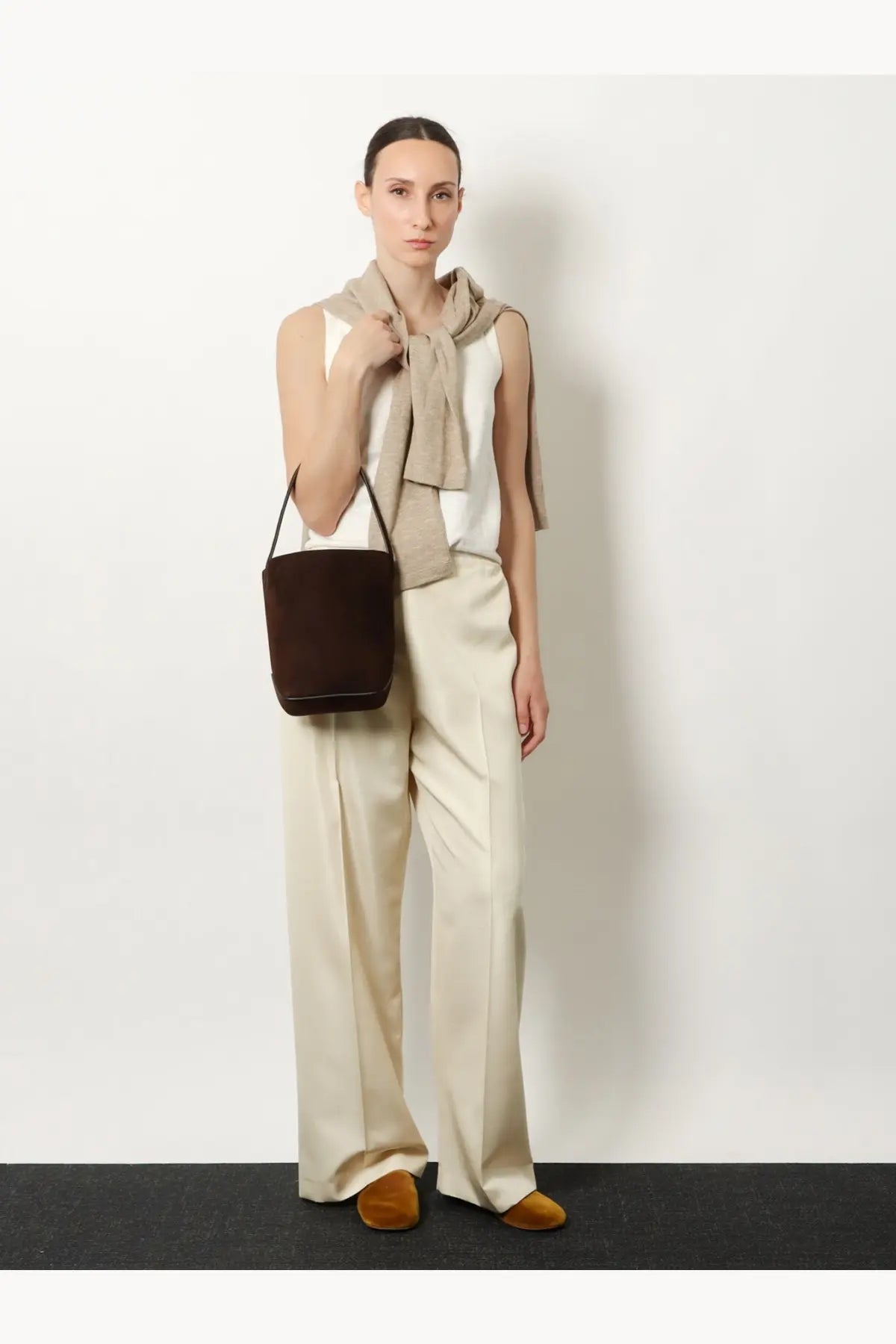 Brown suede bucket bag with black handles featured alongside the row women’s beta silk trousers white