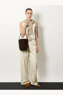 Brown suede bucket bag with black handles featured alongside the row women’s beta silk trousers white