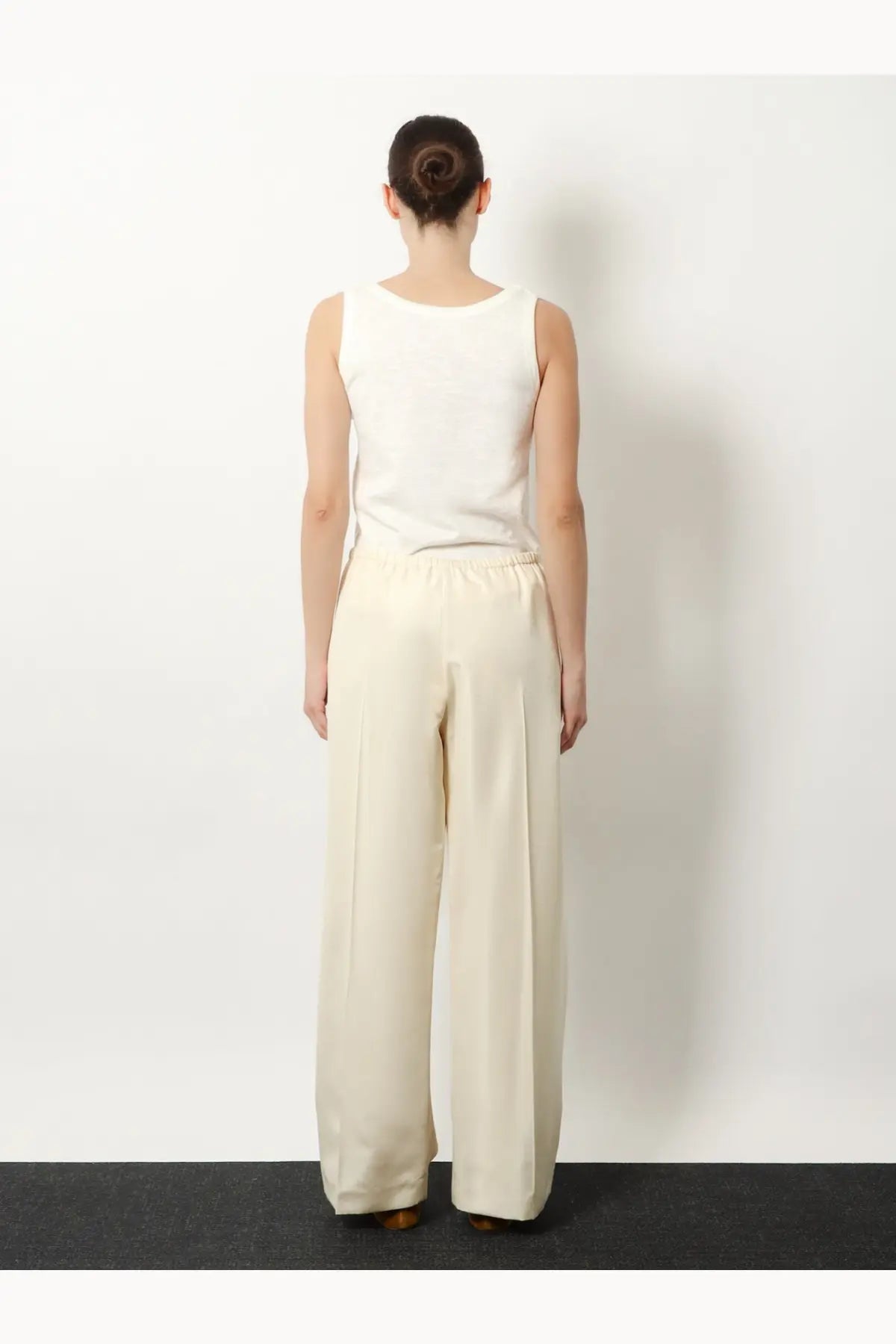 The row women’s beta silk trousers white are cream-colored wide-leg pants with smooth fabric and an elastic waistband