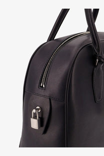 The Row women’s India leather handbag in black with a silver padlock securing the front zipper