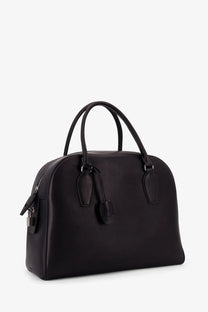 The row women’s india leather handbag black featuring a black leather satchel with rounded top and dual handles