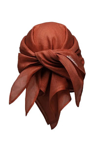 A rust-colored silk scarf tied in a decorative knot featuring the m detail from Ruslan Baginskiy Women’s Sciarpa Con Visore Red