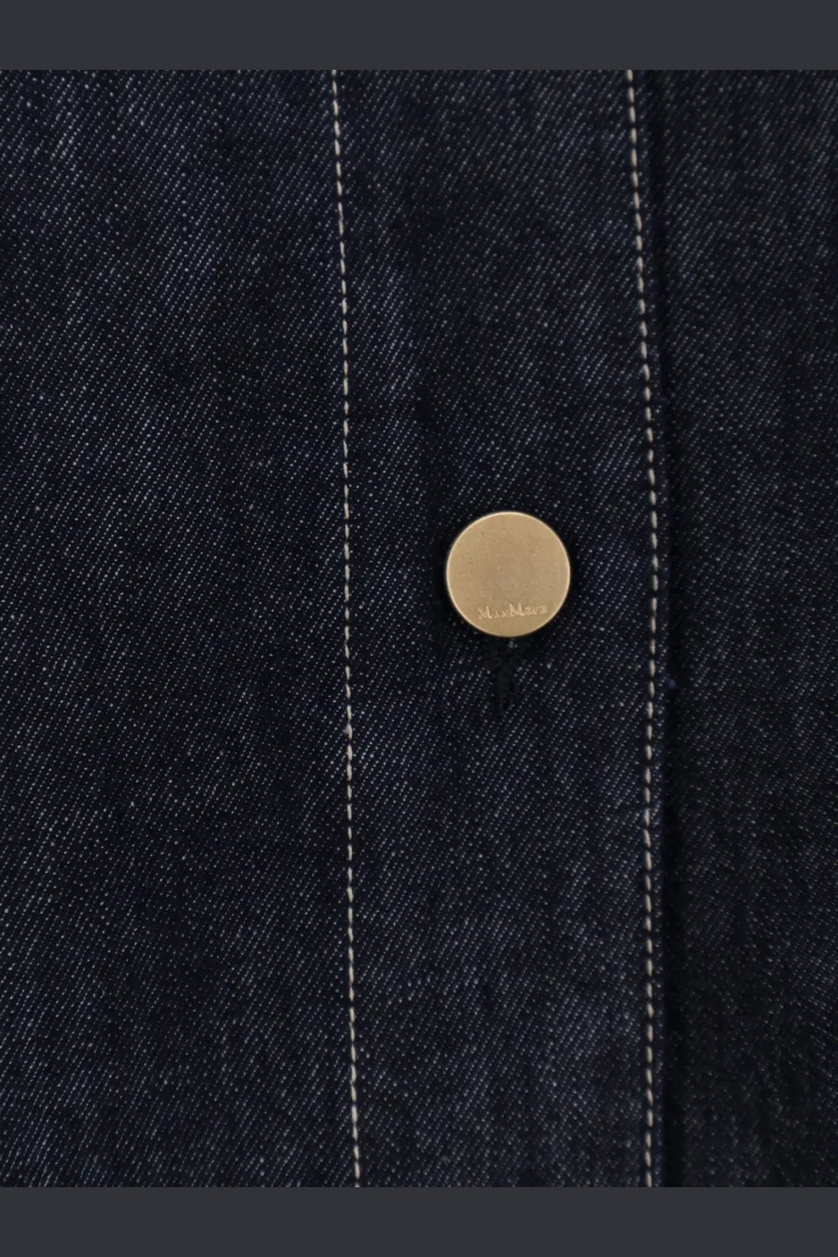 A gold-toned circular button engraved on blue denim fabric of s max mara womens denim shirt