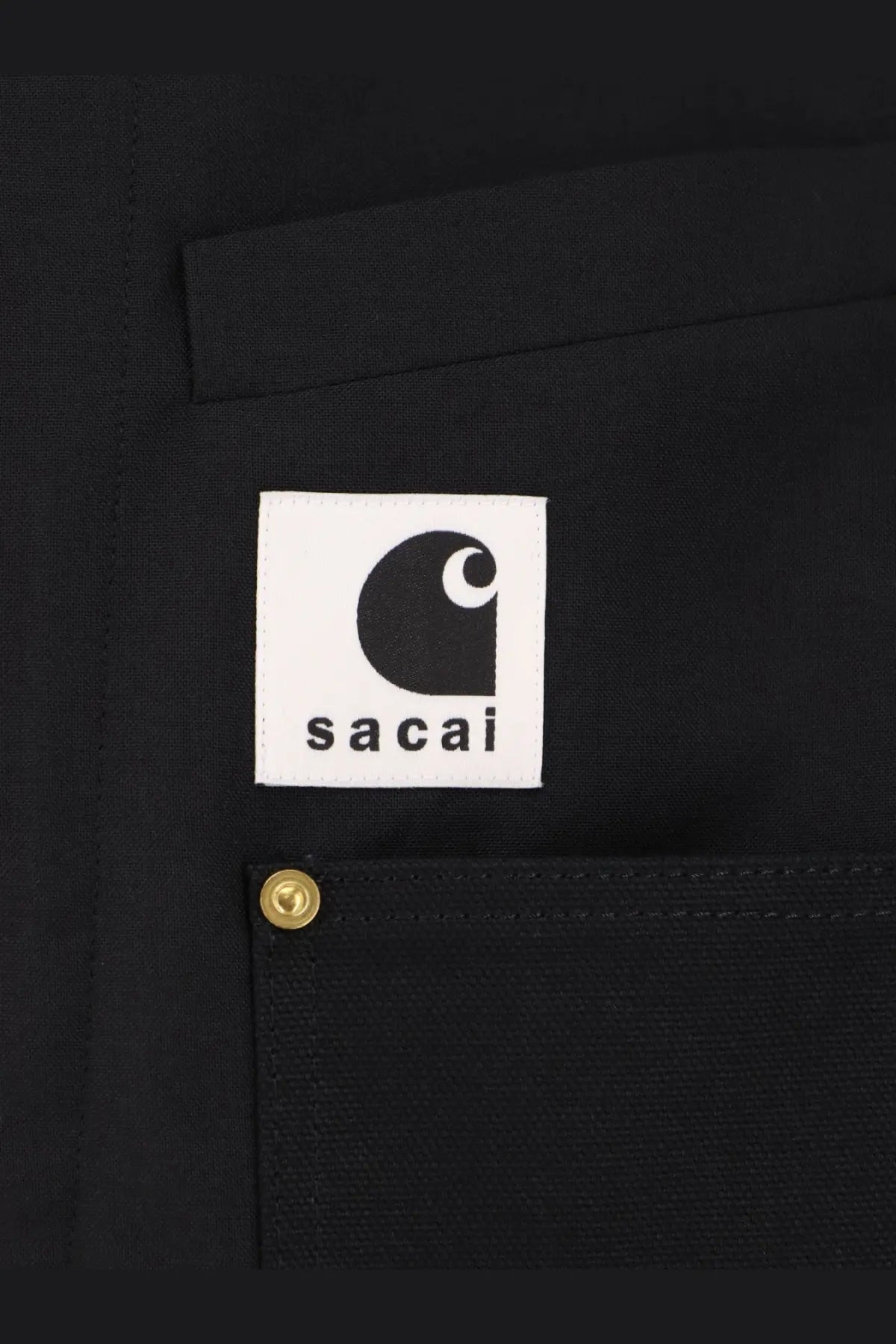 Black carhartt x sacai patch with white label and black curved c logo on sacai men’s black jacket