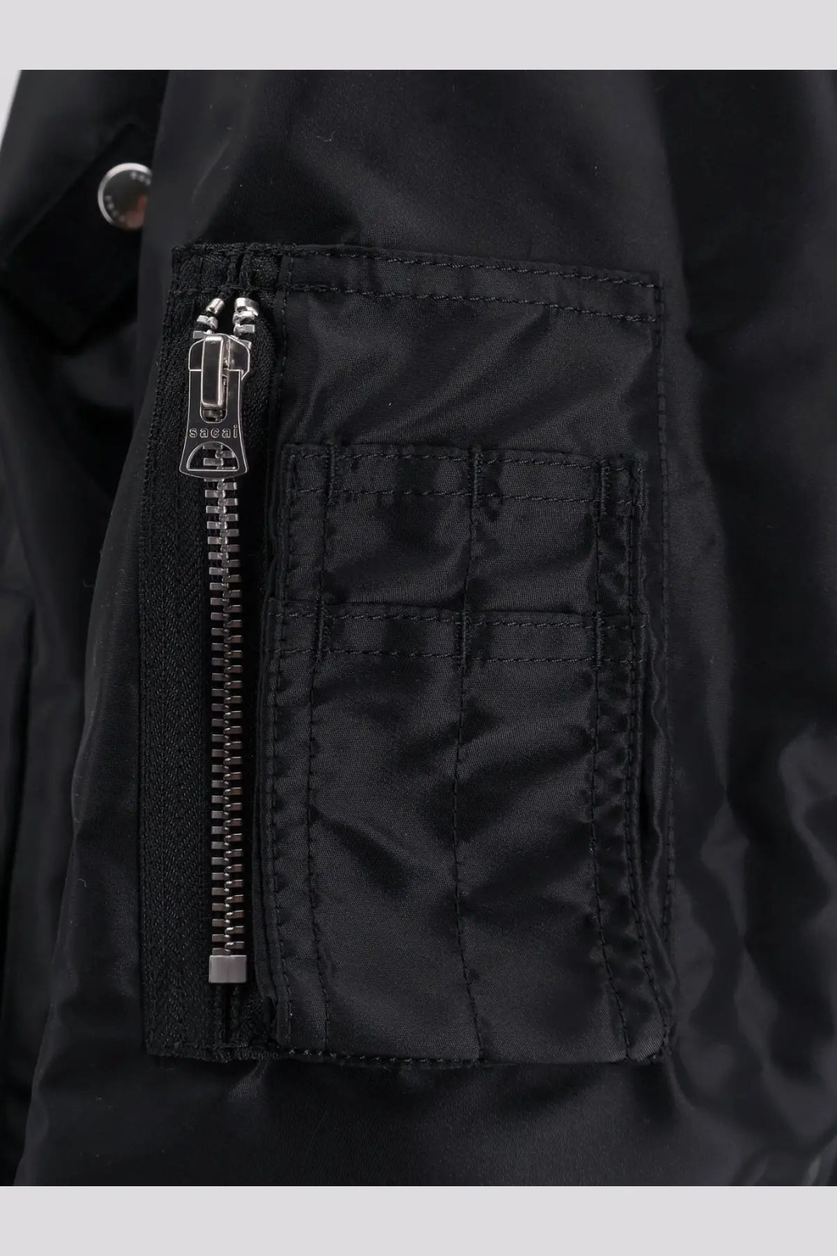 Sacai men’s black nylon bomber jacket pocket with silver zipper and reinforced stitching detail