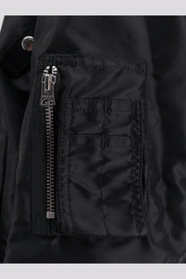 Sacai men’s black nylon bomber jacket pocket with silver zipper and reinforced stitching detail