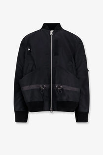Sacai men’s black nylon bomber jacket with silver zipper and dark gray horizontal stripes on the lower front