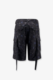Sacai men’s printed cotton cargo shorts in black with a dark blue floral pattern and adjustable side ties