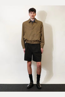 A man wearing a khaki beige saint laurent men’s cassandre cotton bomber jacket with collar and elasticated waistband