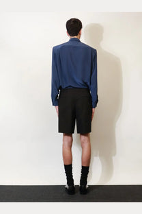 A sleek navy blue satin shirt with classic collar and long sleeves worn over Saint Laurent men’s black certified cotton shorts