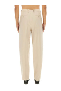 Beige tailored saint laurent men’s light wool trousers with clean straight-leg cut and subtle back pleats shown from the back