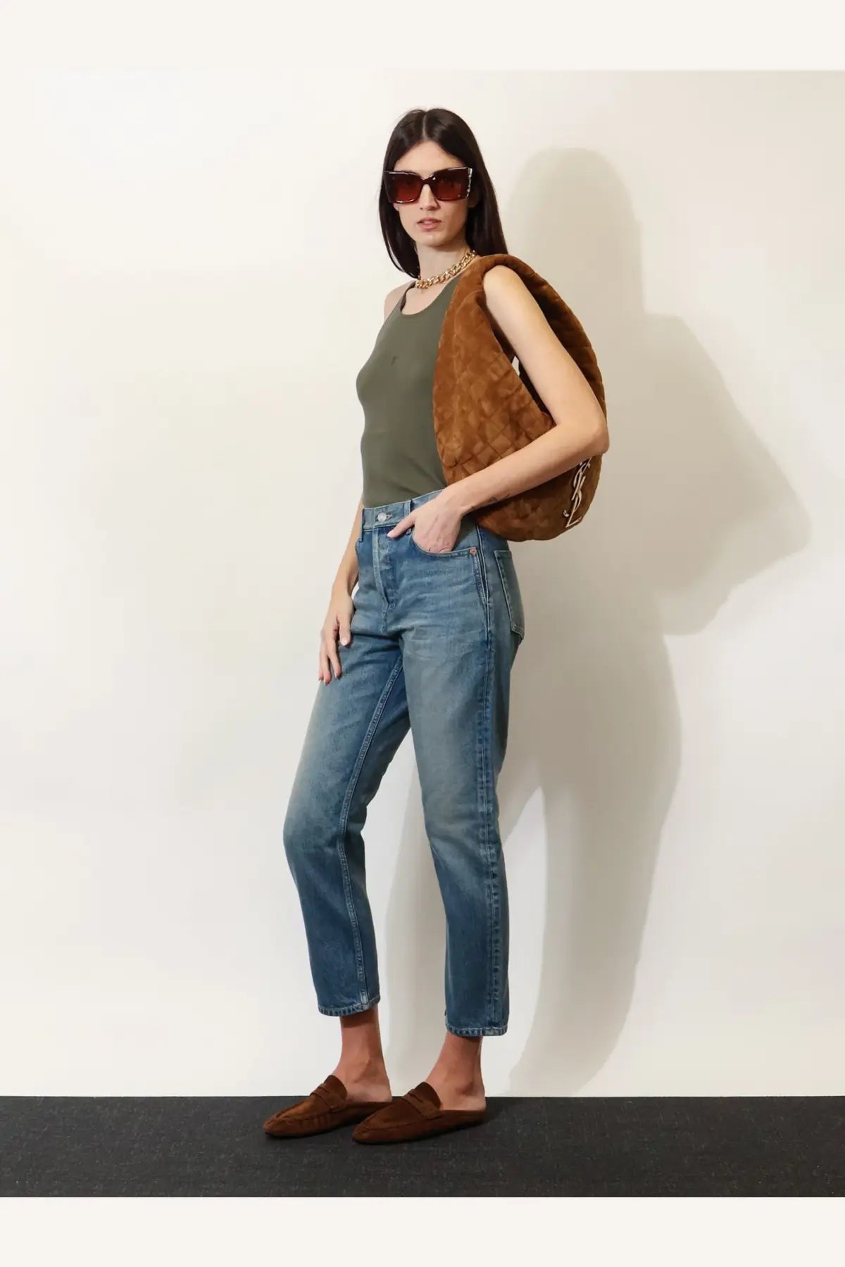 Brown suede quilted shoulder bag with textured plush exterior and subtle stitching details with saint laurent blue denim jeans
