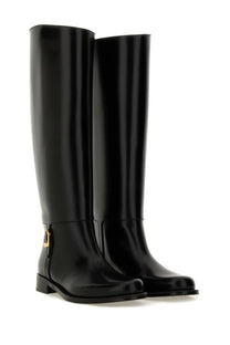 Saint Laurent women’s horny black knee-high boots in patent leather with gold-tone lock detail at the side
