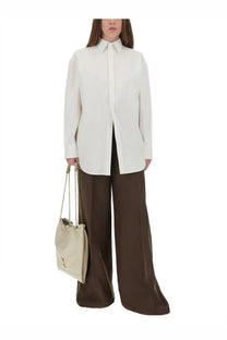 A cream-colored canvas bucket bag with chain strap and ysl logo embroidered, paired with Saint Laurent cotton shirt
