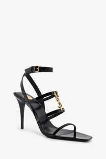 Saint Laurent women’s Cassandre black patent leather high heel sandal with strappy design and gold-tone YSL logo clasp