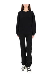 Black oversized crewneck sweatshirt with long sleeves and subtle logo paired with saint laurent women’s low waist jeans nicole black