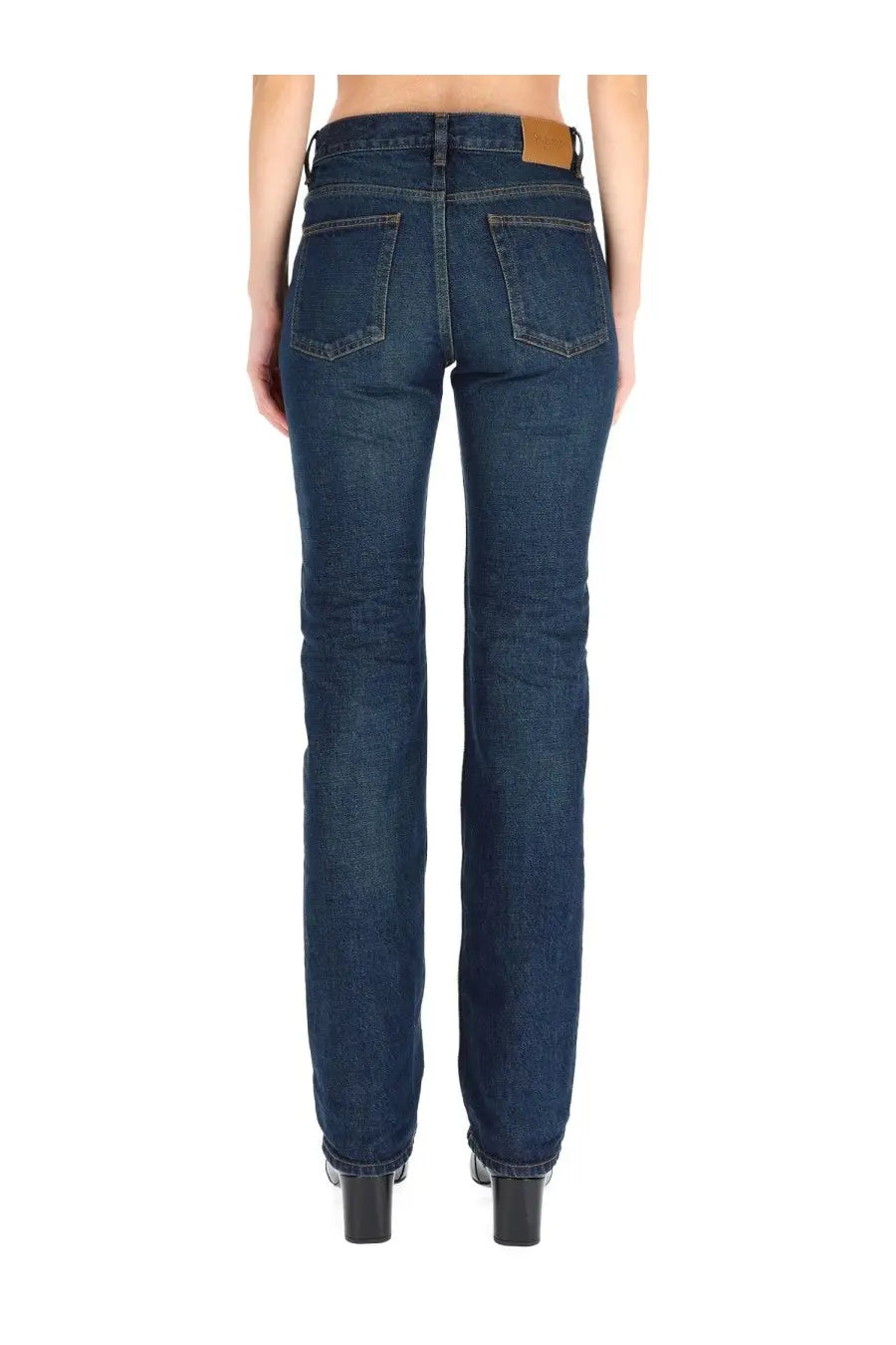 Saint laurent women’s low waist jeans in dark blue denim with straight-leg cut and brown leather brand patch at waistband back view