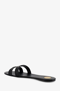 Saint Laurent women’s Mabrouka black leather slide sandal with minimalist design and gold-toned circular heel accent back view