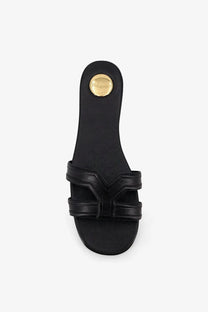 Back view of saint laurent women’s mabrouka black leather slide sandal with gold-tone circular logo on heel