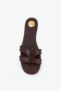 Brown leather Saint Laurent women’s Mabrouka slide sandal showing gold-tone logo plaque on the heel back side