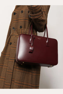 A sleek burgundy leather satchel with structured rectangular shape and top handles Saint Laurent sac de jour handbag