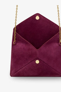 A Saint Laurent women’s deep burgundy velvet envelope clutch with gold chain straps and circular clasps