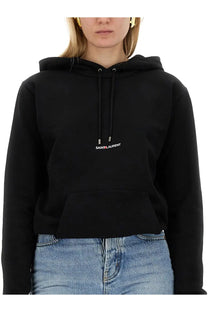 Saint Laurent women’s black cropped hoodie with small white and red logo on the chest made from soft cotton blend